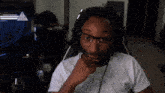 a man wearing glasses and headphones is sitting in front of a sign that says caution