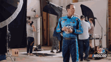 a man in a nascar uniform is standing in a room