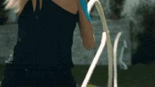 a woman in a black tank top is holding a rope in her hand