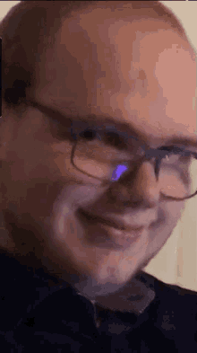 a man wearing glasses is smiling and looking at the camera .