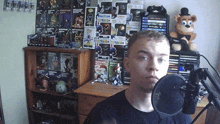 a man stands in front of a microphone in front of a display of funko pop toys