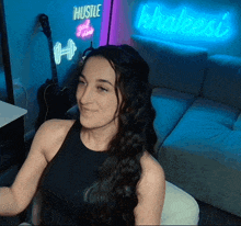 a woman sitting in front of a neon sign that says hustle girl