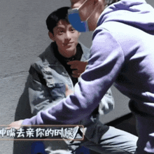a man in a purple sweatshirt is talking to another man