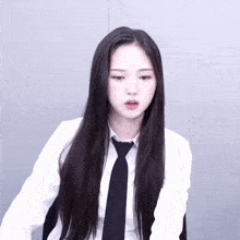 a woman with long black hair wearing a white shirt and tie