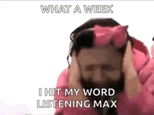a man with a beard and a pink bow on his head is covering his ears .
