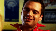 a man in a red jacket is smiling in a room .
