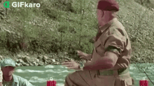 a man in a military uniform is sitting on a rock near a river .