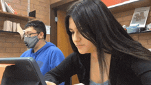 a man wearing a mask sits next to a woman wearing a black sweater