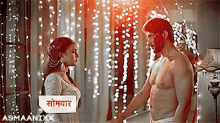 a man without a shirt is holding a woman 's hand in front of a sign that says asmaaniixx