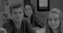 a group of people are sitting at a table in a classroom .