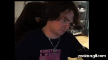 a man is sitting in a chair wearing a necklace and a black shirt .
