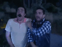 a man with a mustache is making a surprised face while standing next to another man