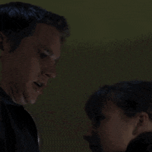 a man and a woman are looking at each other in a dark room .