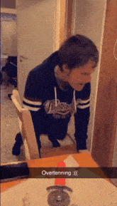 a man wearing a hoodie that says tigers is kneeling down