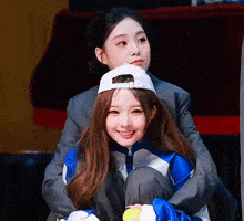 two girls are sitting next to each other with one wearing a hat