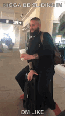 a man with a beard is carrying a suitcase and a cup of coffee with the caption nigga be sliding in