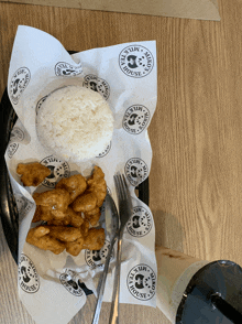 a plate of food with rice and fried chicken on a paper that says milk house