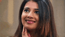 a close up of a woman smiling and touching her face .