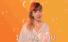 a woman is making a heart shape with her hands and the words `` i love you '' are coming out of her mouth .