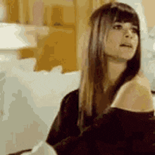 a woman in a black off the shoulder top is sitting on a couch .
