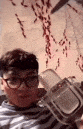 a young man wearing glasses is holding a plastic container .