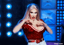 a woman in a red sequined top is dancing in front of a blue background