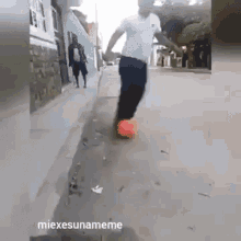 a man is kicking a soccer ball down a sidewalk with the caption " miexesunameme "