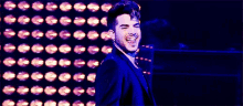 a man in a suit and tie is smiling in front of a wall of lights .