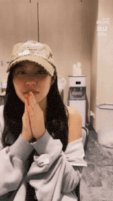 a woman wearing a hat is sitting in a chair with her hands together