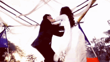 a bride and groom are dancing under a white tent