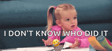 a little girl is sitting at a table with a smiley face and the words `` i don 't know who did it ''