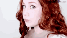 a woman with red hair and blue eyes is making a funny face