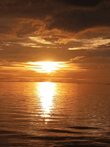a sunset over a body of water with a bridge in the background
