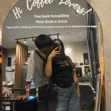 a man and woman are kissing in front of a mirror that says hi coffee lovers