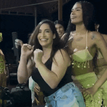 a group of women are dancing and smiling in a dark room