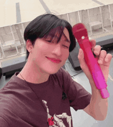 a man in a maroon shirt is holding a red microphone
