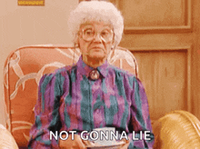 an elderly woman is sitting in a chair holding a cup of tea and saying not gon na lie .