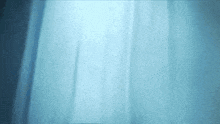 a light shines through a blue curtain in a dark room