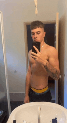 a shirtless man is taking a selfie in front of a mirror .