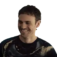 a man with a beard wearing a tie dye shirt smiles for the camera