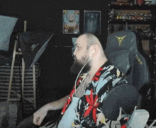 a man with a beard is sitting in a chair wearing headphones and a shirt .