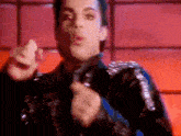 a close up of a man wearing a leather jacket and a blue tie pointing at the camera .