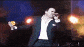 a man in a suit singing into a microphone on a stage