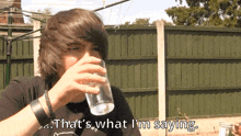 a young boy drinking a glass of water with the words " that 's what i 'm saying " below him