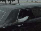 a man is sitting in a black car looking out the window .