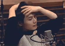 a man is sitting in front of a microphone and holding his hair .