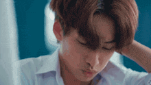 a close up of a young man 's face with his hand on his forehead .
