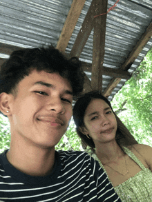 a man and a woman are posing for a picture under a canopy