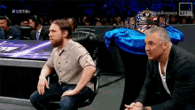 two men are sitting in front of a table with a world heavyweight championship belt