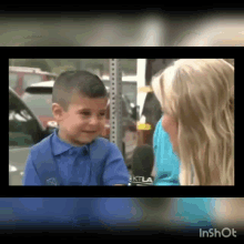 a little boy in a blue shirt is being interviewed by a woman with ktla on her shirt